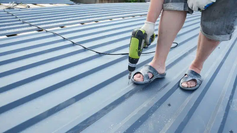 A man drilling a color roof